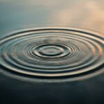 Concentric ripples spreading across calm water, illustrating how vibration therapy travels through the body for back pain relief