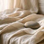 Soft draped linen and a smooth stone evoking released tension — calming wellness imagery