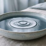 Soft ripples spreading across still water in a pale ceramic bowl, a calming image of tension easing